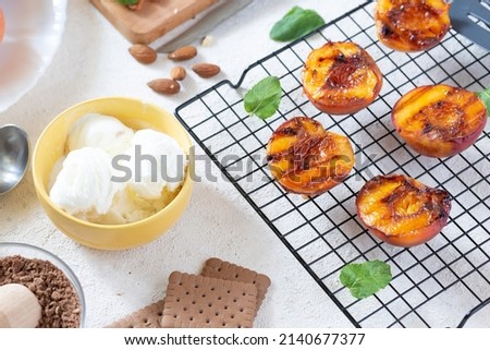 Healthy dessert juicy barbecue peaches with ice cream and almonds on the grill