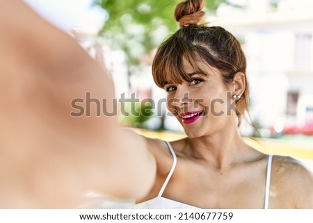 Young hispanic woman smiling happy making selfie by the camera at the city.