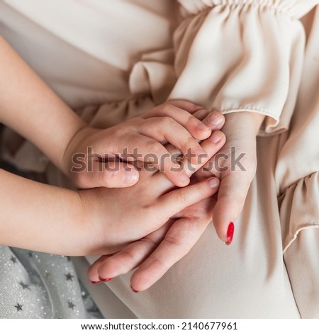 caucasian mom and daughter holding hands close-up, foster family, single mother, todler daughter holding hands, provides support, protection of love, charity and adoption, the concept of family trust