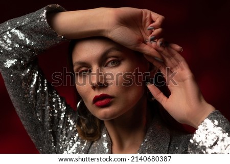 Fashionable beautiful confident  woman with red lips makeup, wearing trendy silver hoop earrings, sequin dress. Studio close up fashion, beauty portrait. Copy, empty space for text