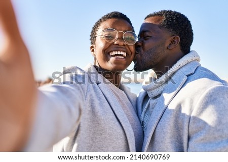 Man and woman couple standing together make selfie by the camera at seaside