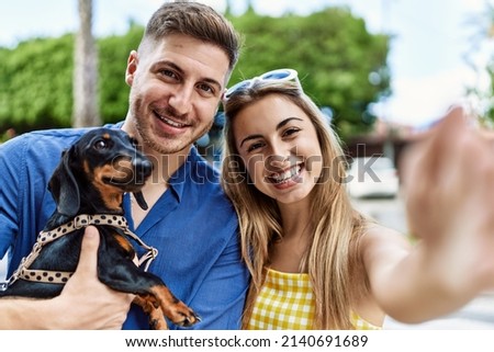 Young caucasian couple smiling happy make selfie by the camera with dog at the city.