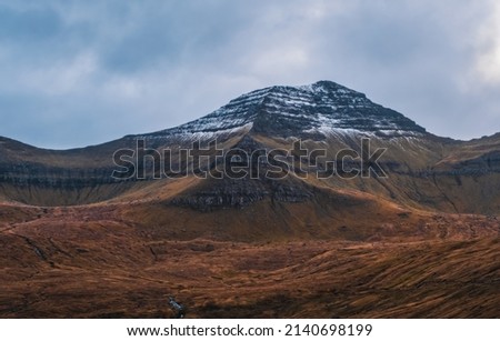 Spectacular views of the scenic snowy mountains on the Faroe Islands near the village Funningur during sunset. November 2021
