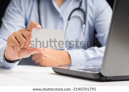 Close-up of hand a doctor holding a blank white paper or mockup name card while sitting in the office. Close-up photo. Business branding concept