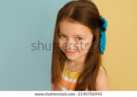 A beautiful cute blue-eyed girl with a big bow in her long hair. Fashion accessories and hair adornments. Copy space Royalty-Free Stock Photo #2140706945