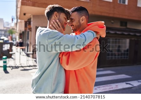 Two man couple hugging each other standing at street