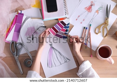 Fashion designer drawing sketch at wooden table, top view
