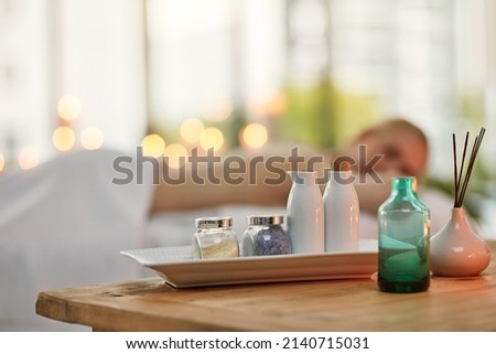 Are you ready to soak up some well-deserved pampering. Cropped shot of various pampering essentials in a spa with a young woman in the background. Royalty-Free Stock Photo #2140715031