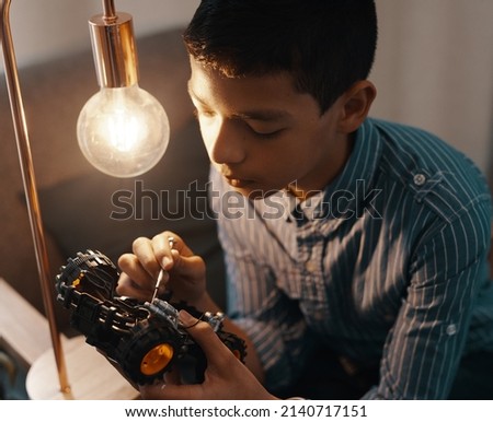 Bright minds come up with bright ideas. Shot of a handsome young boy building a robotic toy car at home. Royalty-Free Stock Photo #2140717151