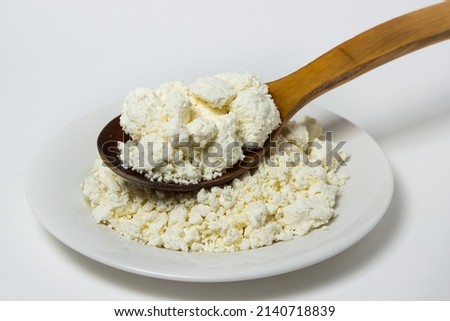 A plate of cottage cheese on a white background. Healthy and tasty dairy product.