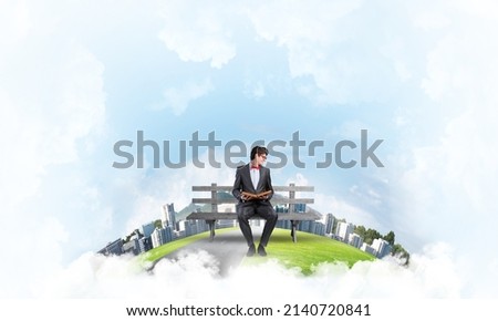 young student sits on a bench with a book in his hands