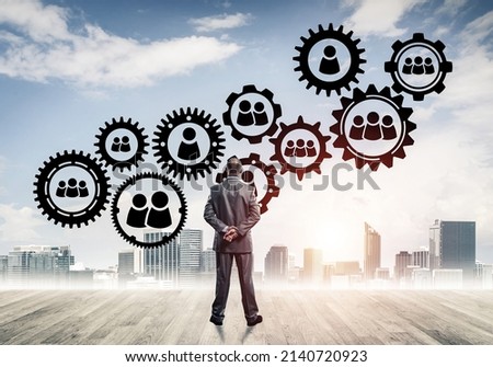 Back view of businessman looking at modern cityscape and gear connection idea