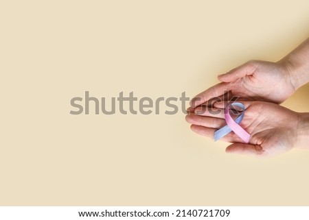 World Thyroid Day. Woman holding Thyroid cancer awareness ribbon in Teal Pink Blue on beige background. Problems with thyroid. Polycystic disease.