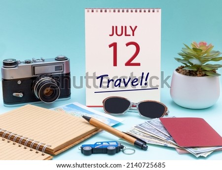 12th day ofJuly. Travel planning, vacation trip - Calendar with the date 12July glasses notepad pen camera cash passports. Summer month, day of the year concept.