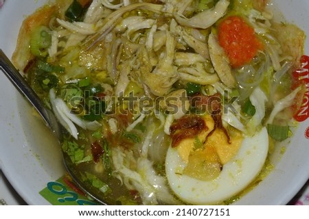 a bowl of chicken soup filled with shredded chicken, egg pieces, white noodles, cabbage pieces