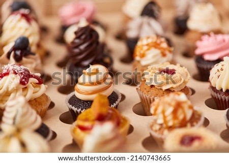 Many different small colorful cupcakes with decorations in a pastry shop Royalty-Free Stock Photo #2140743665