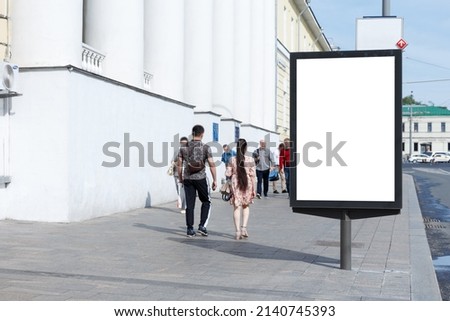 Vertical billboard for advertising and text in the city. Citizens on a summer day on the sidewalk. Mock-up.