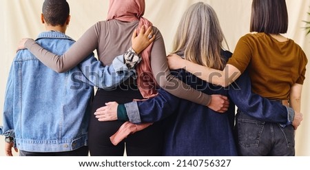 International Women's Day rear view portrait of four women standing with arms around each other in solidarity Royalty-Free Stock Photo #2140756327