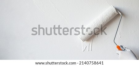 Roller Brush Painting, Worker painting on surface wall  Painting apartment, renovating with white color  paint. Leave empty copy space to write descriptive text beside.