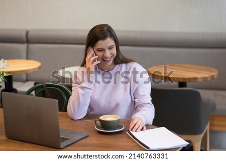 The woman is wearing a lilac purple color of the year 2022 very peri mock up sweatshirt. Using modern technologies at work. Concept: using a phone talking on a smartphone freelance work 