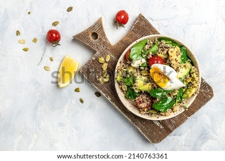 Keto diet plate quinoa, avocado, egg, tomatoes, spinach and sunflower seeds on light background. Healthy food, ketogenic diet, diet lunch concept, place for text, top view.