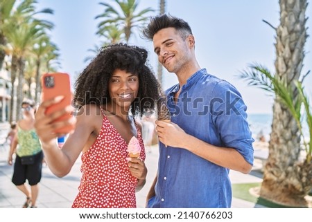Man and woman couple eating ice cream make selfie by the smartphone at seaside