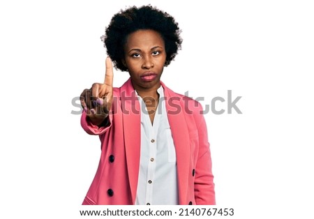 African american woman with afro hair wearing business jacket pointing with finger up and angry expression, showing no gesture 