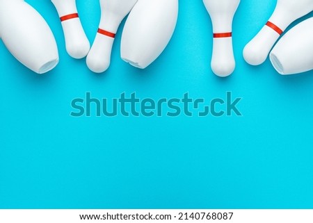 Minimalist photo of bowling pins over turquoise blue background. Flat lay top down image of white bowling pins with copy space.