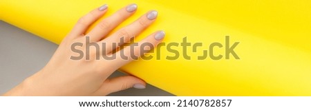Beautiful womans hand with shiny nail design on gray and yellow background