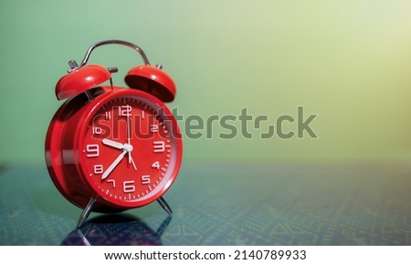 Retro red alarm clock in front of green wall with copy space, background