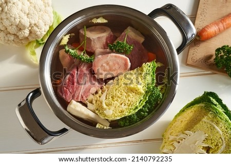 Ingredients for preparing homemade broth or soup in a pot - fresh marrow bones, beef meat and vegetables