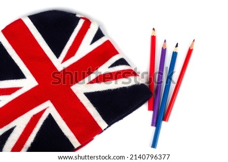 Winter knitted hat with a pattern of the UK flag and colored pencils on a white background.