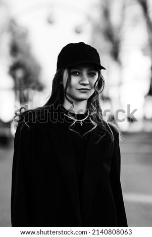 Portrait of a beautiful smiling girl in a black baseball cap. Black and white photo.