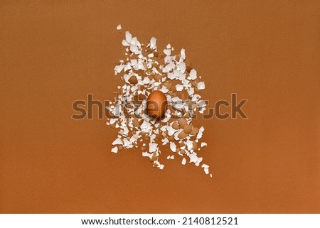 Concept of strength, power and stamina. Whole egg and eggshell on brown background. Royalty-Free Stock Photo #2140812521