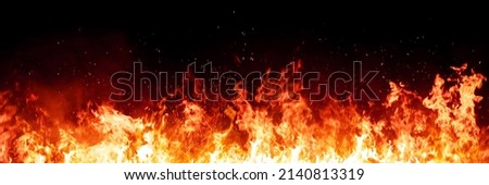 Burning red hot sparks rise from large fire in the night. Fire flames sparks background. Abstract dark glitter fire particles lights.