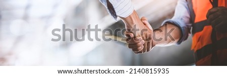 Two engineer shaking hands with deals and congratulations on success, panorama image use for cover design. Royalty-Free Stock Photo #2140815935