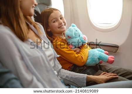 Joyful little girl and woman sitting in passenger airplane Royalty-Free Stock Photo #2140819089