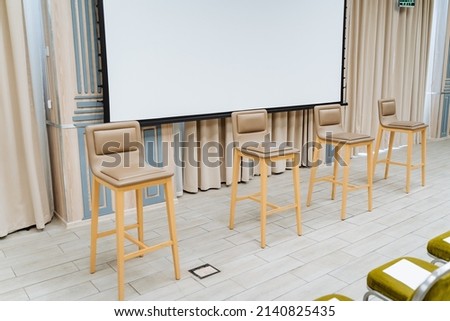 Conference hall for business events. White projector screen on the wall. Bar stools. High quality photo