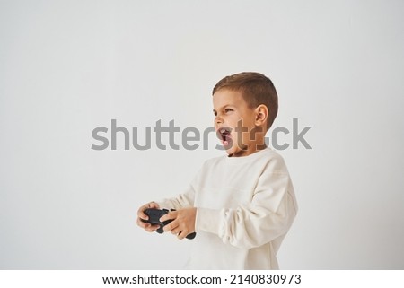 Emotional child with gamepad on white background. Boy is playing games