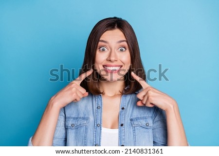 Photo of impressed funny woman wear jeans shirt pointing fingers teeth isolated blue color background