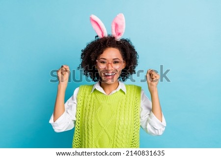Portrait of adorable cheerful female raise fists in triumph win prize money lottery isolated on blue color background