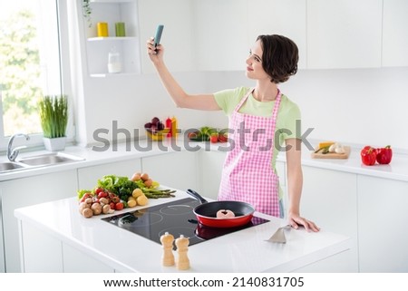 Portrait of attractive charming lady hold telephone make selfie recording video prepare frying salmon indoors