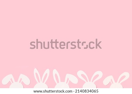 White paper rabbit heads on a pink background with copy space