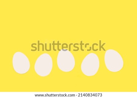 White paper eggs on a yellow background with copy space