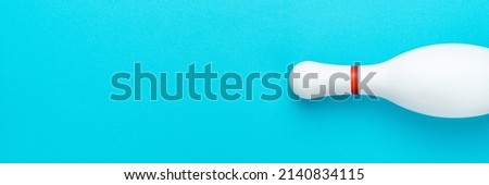 Flat lay top down image of white bowling pin with copy space. Minimalist photo of bowling pin over turquoise blue background.