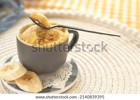 cupcake in a mug with banana pieces. Banana cupcake on a light background. vanilla biscuit in a mug. The concept of a dessert in the microwave. bananas cake. High quality photo Royalty-Free Stock Photo #2140839395