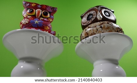 2 wooden owls with colored decorations on a porcelain base