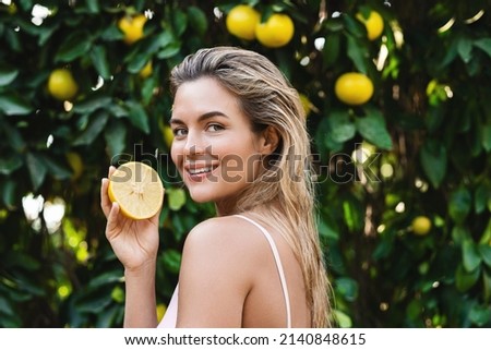 Outdoor portrait of beautiful woman with smooth skin with a lemon fruit in her hands Royalty-Free Stock Photo #2140848615