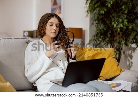 Ambitious girl works remotely from home, sits on living room with laptop customer service, claims office. Sends an email to his coworkers, signs reports