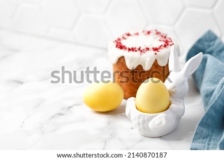 Easter eggs yellow color and Traditional Russian Easter Cake with glaze top. Light Easter-Orthodox holiday background. Copy space